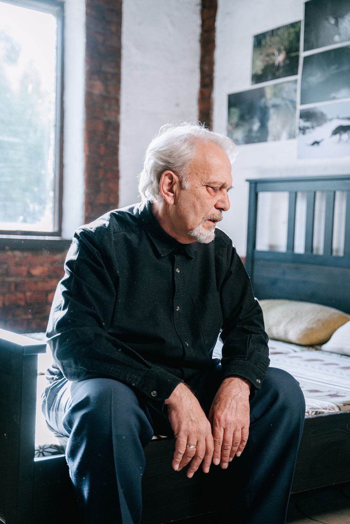 Older man sitting on the edge of his bed looking tired and worried, awake because of frequent nighttime urination